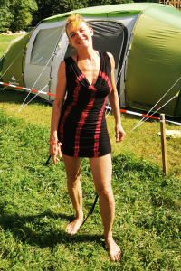 Bild mit einer Frau auf einer Wiese mit Zelt im Hintergrund.